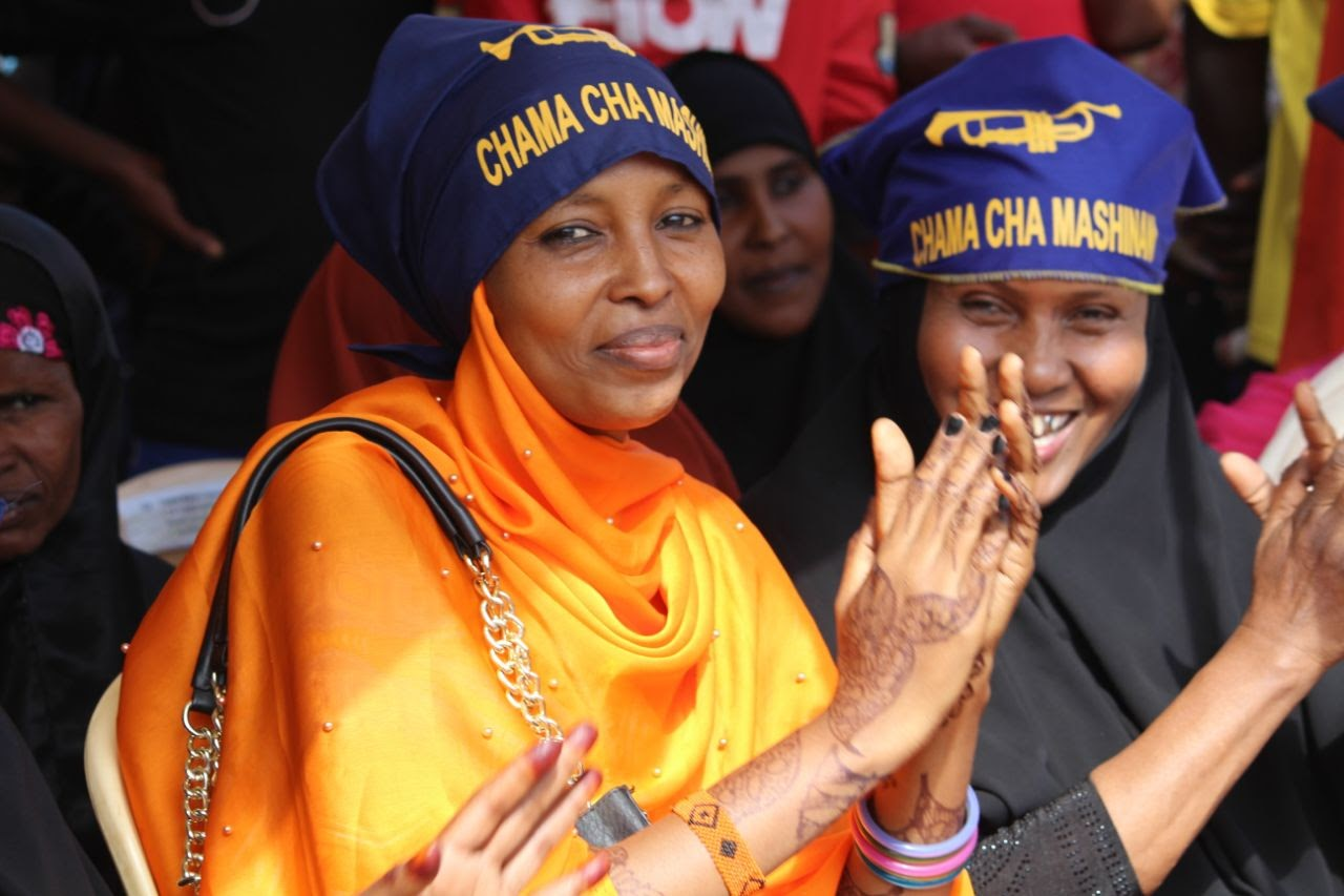 Women in CCM headscarves applauding at a party gathering